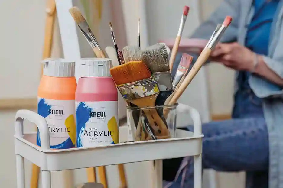 Close‑up of KREUL Triton Acrylic Liquid bottles showing flowing acrylic paint in bright colors.