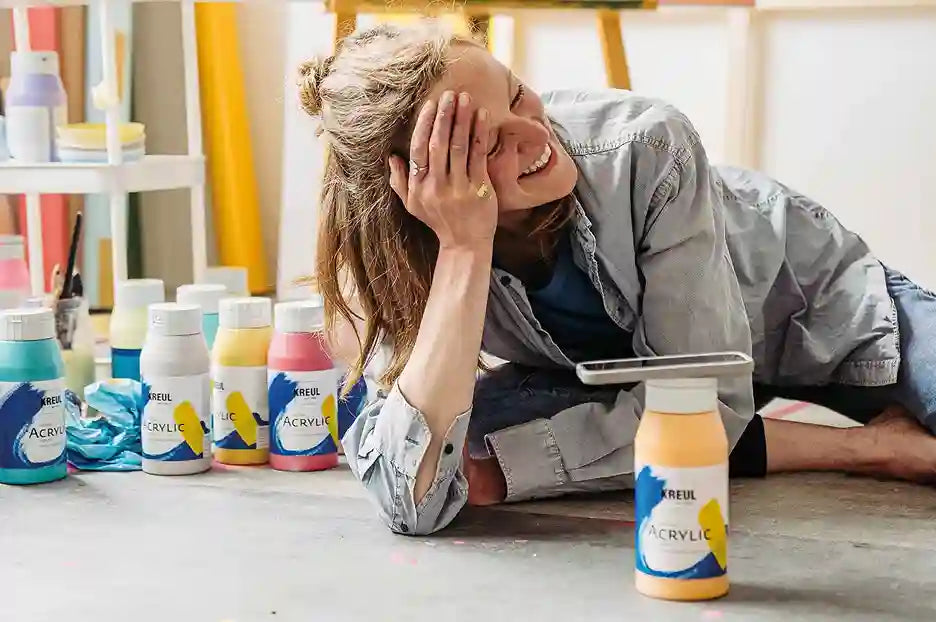 Artist pouring KREUL Triton Acrylic Liquid from a bottle onto a canvas for large-scale artwork.