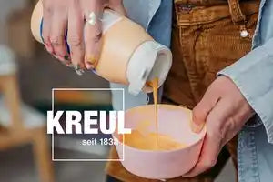 Artist pouring KREUL Triton Acrylic Liquid from a bottle onto a canvas for large-scale artwork.