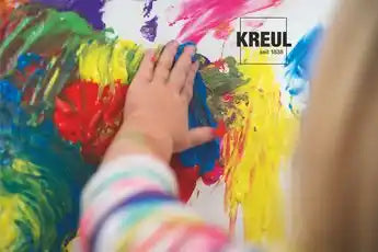MUCKI Finger Paint white 150 ml jar with colorful children’s artwork in the background.