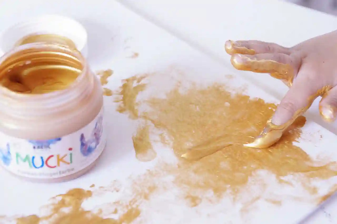 MUCKI gleaming finger paint gold colour applied with fingers