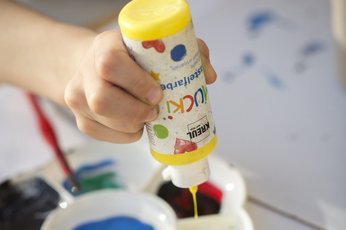 MUCKI Craft Paint bottle applying yellow paint on paper